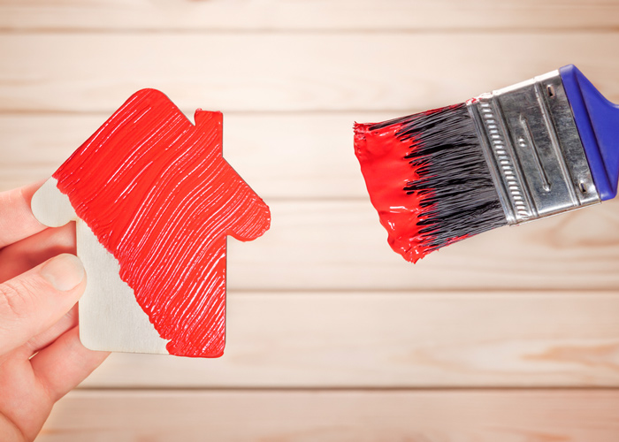 immagine di un pennello con vernice rossa su modellino di casa